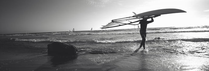 Man carrying a surfboard over his head on the beach, Santa Cruz, California, USA