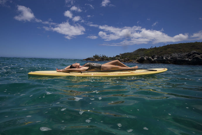 Woman relaxing on paddleboard in Pacific Ocean, Hawaii, USA